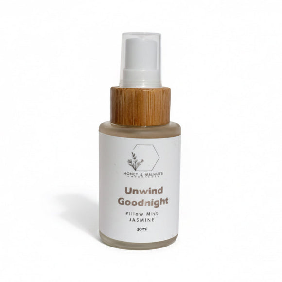 Bottle of 'Unwind Goodnight' pillow mist with wooden cap on a transparent background